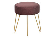 Close-up of plush blush pink upholstery and thin gold metal legs on round ottoman